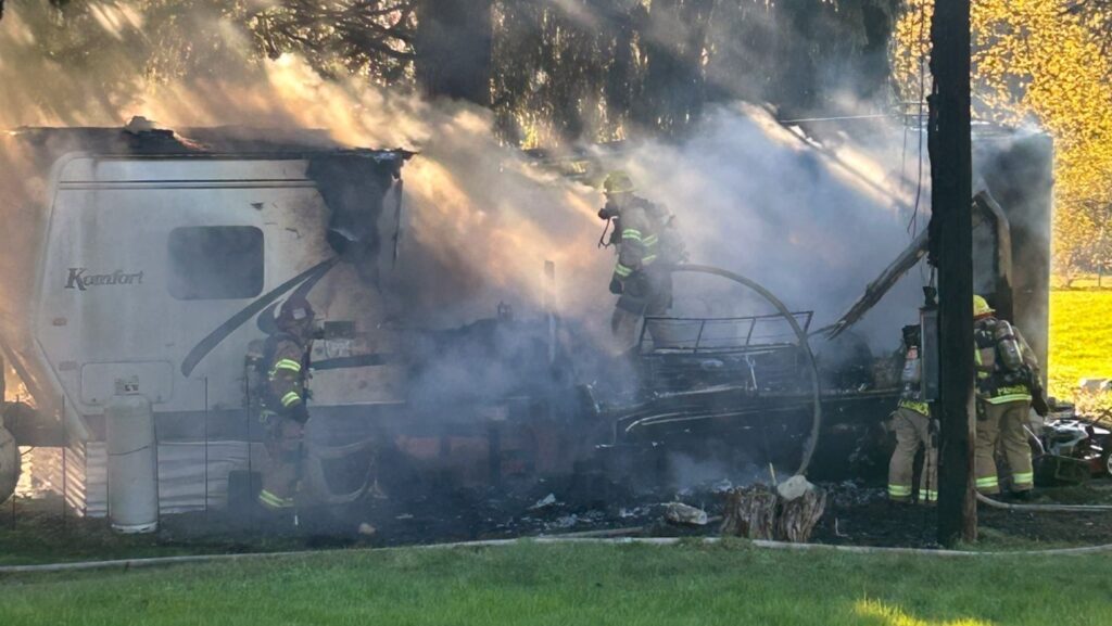 Bomberos combaten un incendio en un tráiler rodeado de humo en Woodinville, mientras el fuego consume parte de la estructura.