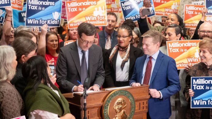 Bob Ferguson El gobernador Bob Ferguson firma la ley del «Impuesto a los millonarios» en la Sala de Recepciones del Estado, en Olympia, el 30 de marzo de 2026. (Foto cortesía de la Oficina del Gobernador del Estado de Washington)