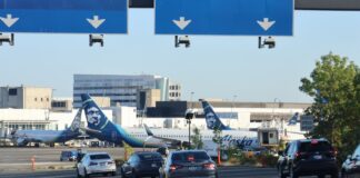 Alaska Airlines aumenta sus tarifas de equipaje en 2026 Carretera de acceso al Aeropuerto Internacional de Seattle-Tacoma (SEA). Aeronaves de Alaska Airlines permanecen en pista al fondo — Imagen: Latino Herald ™