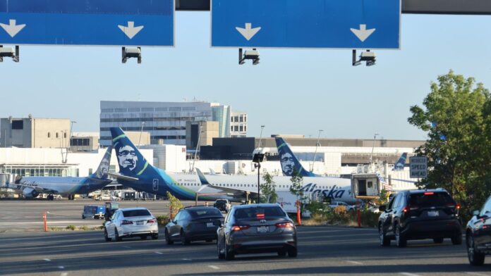 Aeronaves de Alaska Airlines Carretera de acceso al Aeropuerto Internacional de Seattle-Tacoma (SEA). Aeronaves de Alaska Airlines permanecen en pista al fondo — Imagen: Latino Herald ™