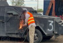 FGR destruye 18 vehículos con blindaje artesanal en México Trabajador con chaleco de seguridad corta con soplete la estructura metálica de un vehículo blindado artesanal tipo “monstruo”, generando chispas mientras forma parte de un operativo de destrucción en México.