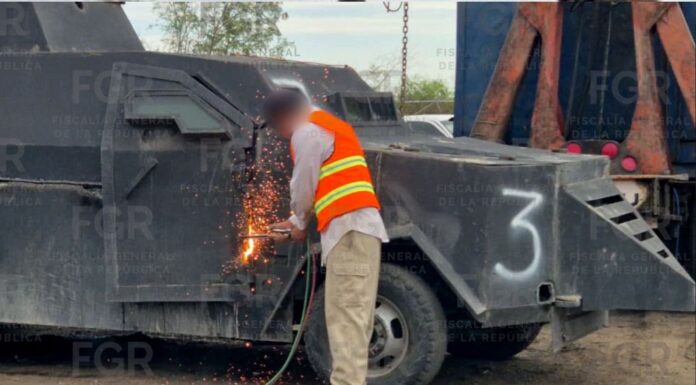 FGR destruye 18 vehículos con blindaje artesanal en México Trabajador con chaleco de seguridad corta con soplete la estructura metálica de un vehículo blindado artesanal tipo “monstruo”, generando chispas mientras forma parte de un operativo de destrucción en México.