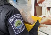 Bothell mantiene operativo: investigan masajes por presunta prostitución Agente de la policía de Bothell sostiene una caja con evidencia frente a un establecimiento de masajes durante un operativo.
