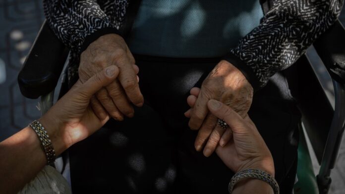 Una mujer sostiene las manos de su madre anciana. (Foto de AP/Bernat Armangue)