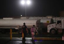Golpe al huachicol: desmantelan grupo dedicado al robo de gas licuado en México Un agente de la Policía Federal y un guardia de seguridad caminan cerca de camiones cisterna en un centro de almacenamiento y distribución de combustible de Petróleos Mexicanos. (Foto AP/Félix Márquez)
