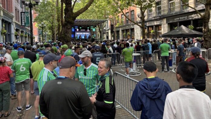 Varias personas se congregaron en Occidental Park, en el corazón del histórico distrito de Pioneer Square. Muchos vestían camisetas del Sounders FC o los colores verde y azul del equipo — Imagen: SDOT