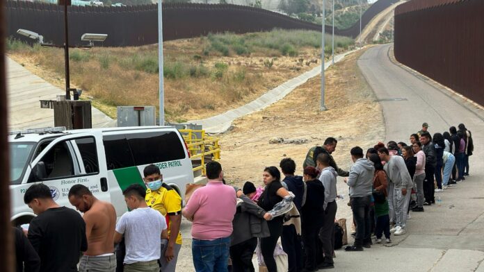 Migrantes en busca de asilo hacen fila a la espera de ser procesados tras cruzar la frontera el 5 de junio de 2024, en San Diego, California. (Foto de AP/Eugene Garcia, Archivo)