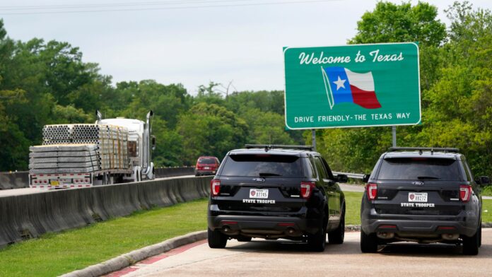 Dos vehículos de la Patrulla Estatal de Texas aguardan estacionados junto a un letrero de bienvenida en el poblado de Orange, cerca de la frontera con Louisiana.(Foto AP/David J. Phillip)