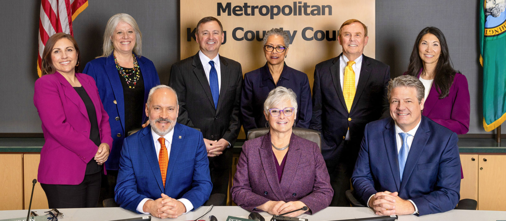 Miembros del concejo del condado de King de Izquierda a derecha, de pie: Teresa Mosqueda  (Distrito 8), Claudia Balducci (Distrito 6), Rod Dembowski  (Distrito 1), Rhonda Lewis  (Distrito 2), Peter von Reichbauer (Distrito 7),  Steffanie Fain  (Distrito 5). Sentados: el vicepresidente del consejo, Jorge L. Barón  (Distrito 4), la presidenta del consejo,  Sarah Perry (Distrito 3), y el vicepresidente del consejo,  Reagan Dunn  (Distrito 9) — Foto: Condado de King 