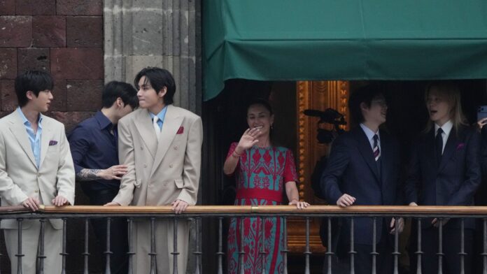 Integrantes de BTS y Claudia Sheinbaum saludan desde un balcón del Palacio Nacional ante miles de fans reunidos en el Zócalo de Ciudad de México.
