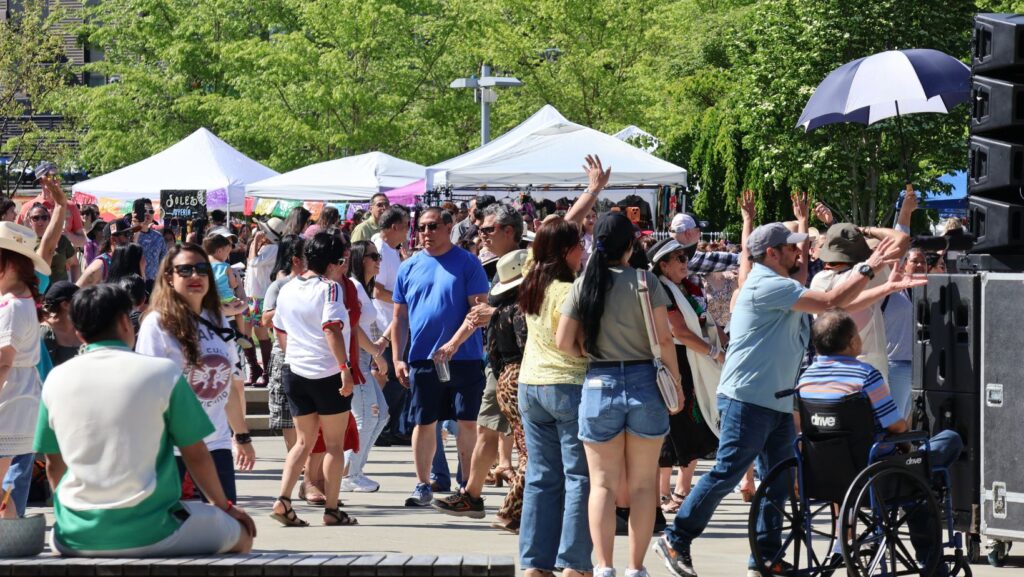 Multitud baila y celebra frente al escenario durante el festival del Cinco de Mayo en Redmond con música en vivo.