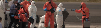Pasajeros son rociados con desinfectante por funcionarios del gobierno español antes de abordar un avión después de desembarcar del crucero MV Hondius afectado por el hantavirus en el aeropuerto de Tenerife en las Islas Canarias, España
