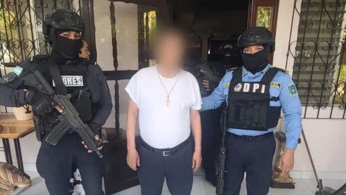 Dos agentes de la DPI custodian a un hombre detenido durante un operativo relacionado con la investigación por el asesinato del ambientalista Juan López en Honduras.