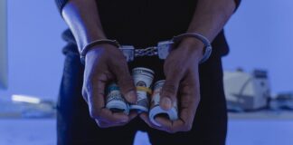 Sujeto despoja a su propia abuela de 500 mil dólares y termina en la cárcel A Person with handcuffs Holding a Sum of Rolled Cash