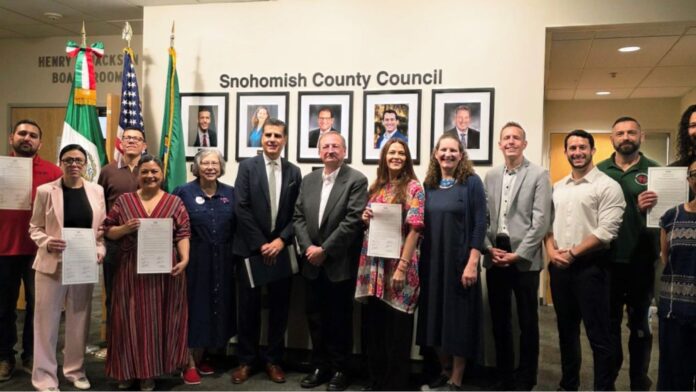 Marines Scaramazza, Latino Herald, Cathy Liu Scott, expresidenta de la Liga de Mujeres Votantes del Condado de Snohomish, Gerardo Javier Guiza Vargas, cónsul adjunto del Consulado de México en Seattle, el ejecutivo del Condado de Snohomish Somers, la comisionada de PUD Dra. Julieta Altamirano-Crosby, la presidenta y el vicepresidente del Condado de Snohomish Megan Dunn y Nate Nehring, el concejal del Condado de Snohomish Jared Mead y Zac McCown, presidente del Sindicato de Carpinteros Local 425, con residentes conmemorando el Cinco de Mayo en la reunión del Consejo del Condado de Snohomish el 5 de mayo de 2026 — Imagen: Lynnwood Times | Mario Lotmore.