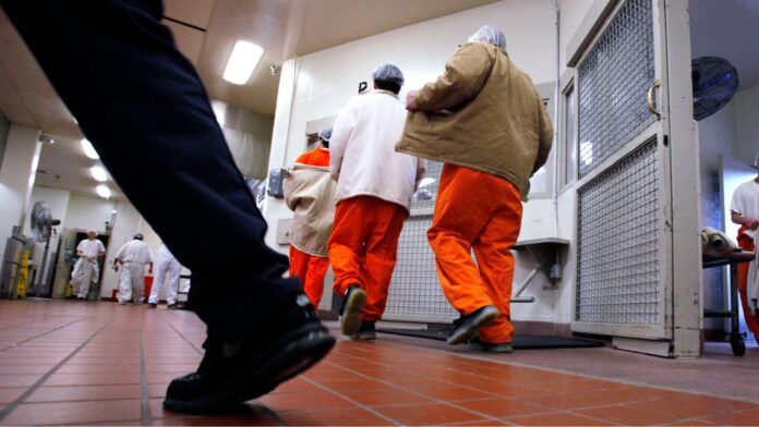 Foto de archivo de un oficial correccional pasando mientras los reclusos se dirigen a sus asignaciones de trabajo dentro de un área de servicio de alimentos en el Centro Correccional de Washington, en Shelton, Washington (Foto AP/Elaine Thompson)
