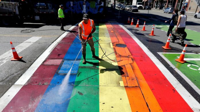 Un empleado municipal limpia a presión un cruce peatonal pintado con los colores del arcoíris, como parte de una limpieza anual en el vecindario de Capitol Hill, en Seattle. (Foto AP/Elaine Thompson)