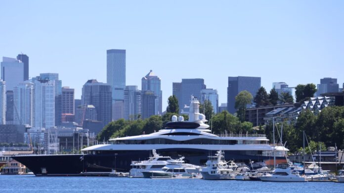 Yate LaunchPad Vista panorámica del yate LaunchPad, asociado a Mark Zuckerberg, navegando o atracado cerca del lago Union en Seattle, con el horizonte del centro de la ciudad visible al fondo y varias embarcaciones menores en primer plano.