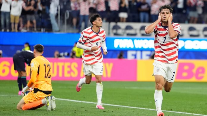 Giovanni Reyna celebra tras marcar el cuarto gol de Estados Unidos frente a Paraguay durante un partido del Grupo D de la Copa Mundial de la FIFA 2026 en Inglewood, California. El mediocampista corre junto a la línea de banda con las manos sobre las orejas mientras aficionados estadounidenses celebran en las gradas.