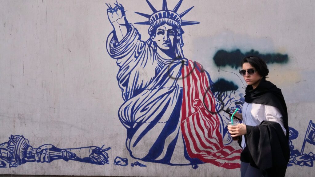 Una mujer pasa junto a un mural antiestadounidense en la pared de la antigua embajada de Estados Unidos, ahora convertida en museo, en Teherán, Irán, el viernes 12 de junio de 2026. (Foto AP/Vahid Salemi)