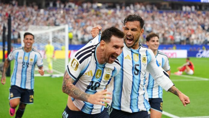 Leandro Paredes (5) agarra de la camiseta a su compañero Lionel Messi al celebrar el segund gol de Argentina en la victoria 2-0 ante Austria en el Grupo J del Mundial, el lunes 22 de junio de 2026, en Arlington, Texas. (AP Foto/Julio Cortez)