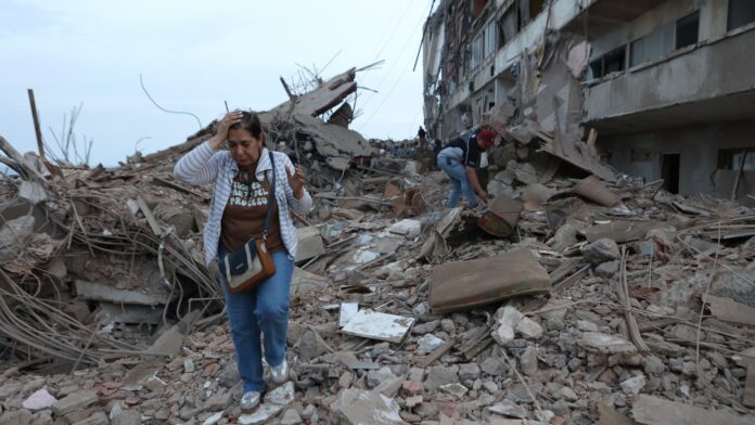 Residentes caminan entre los escombros del edificio dañado en terremotos el día anterior en Catia La Mar, Venezuela, el jueves 25 de junio de 2026. (Foto AP/Pedro Mattey)