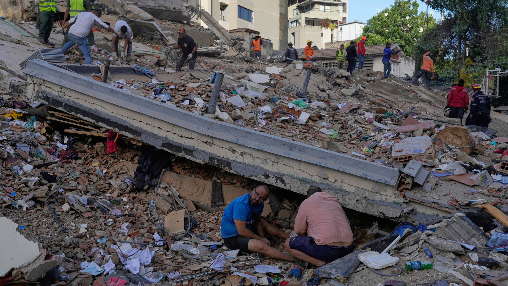 Residentes y rescatistas buscan entre los escombros de un edificio que se derrumbó en los terremotos que sacudieron el día anterior en Caracas, Venezuela, jueves 25 de junio de 2026. (AP Foto/Ariana Cubillos)