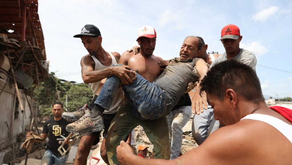 Vecinos llevan a un hombre rescatado de los escombros de un edificio derrumbado el día después de que los terremotos golpearan La Guaira, Venezuela, el jueves 25 de junio de 2026. (Foto AP/Pedro Mattey)