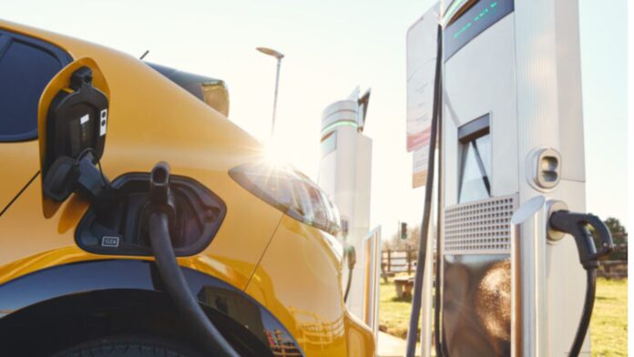 Vehículo eléctrico enchufado Vehículo eléctrico enchufado en una estación de carga para vehículos eléctricos utilizando un cargador rápido — Imagen: Departamento de comercio del estado de Washington