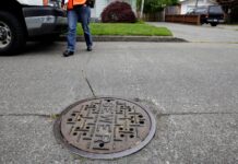 Condado King aprueba aumento en tarifas de alcantarillado y seguirán subiendo Una trabajadora de mantenimiento camina junto a una alcantarilla en Seattle, mientras el condado King planea aumentar las tarifas de drenaje. (Foto AP/Ted S. Warren)