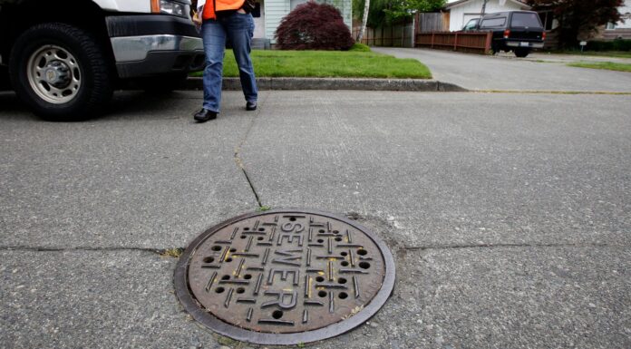 Condado King aprueba aumento en tarifas de alcantarillado y seguirán subiendo Una trabajadora de mantenimiento camina junto a una alcantarilla en Seattle, mientras el condado King planea aumentar las tarifas de drenaje. (Foto AP/Ted S. Warren)