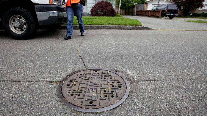 Una trabajadora de mantenimiento camina junto a una alcantarilla en Seattle, mientras el condado King planea aumentar las tarifas de drenaje. (Foto AP/Ted S. Warren)