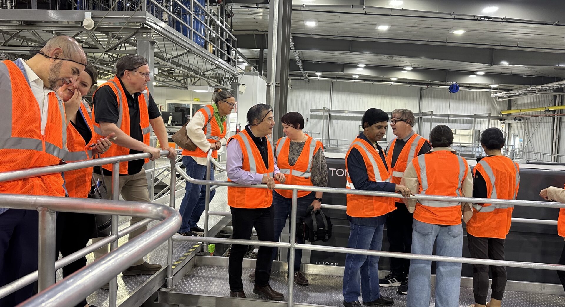 Representantes diplomáticos, autoridades estatales y personal de Monson Fruit recorren una planta empacadora de cerezas en el Valle de Yakima durante una visita agroindustrial organizada para conocer procesos de producción y exportación agrícola