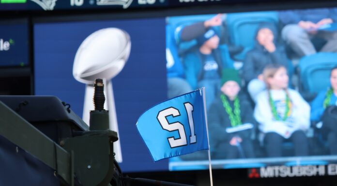 Seattle Seahawks acuerdan su venta por un récord de $9,600 millones al grupo de Vinod y Neal Khosla El trofeo Vince Lombardi y una bandera con el número 12 de los Seattle Seahawks durante la celebración del campeonato del Super Bowl en Lumen Field, en Seattle, en febrero de 2026. Al fondo se observan aficionados siguiendo el evento desde las gradas. Foto: Latino Herald™