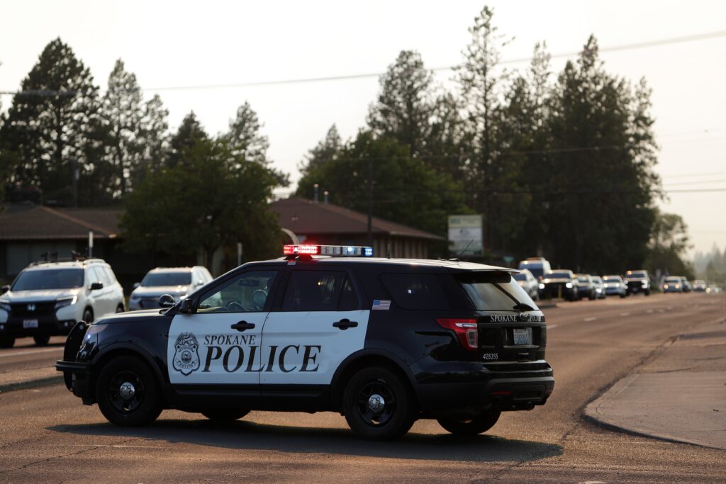 Bloque policial W. Avenida Francis en N. Monroe St. mientras los vehículos abandonan un área de evacuación de Old Trails Fire, el sábado 1 de agosto de 2026, en Spokane, Washington. (Foto AP/Joven Kwak)