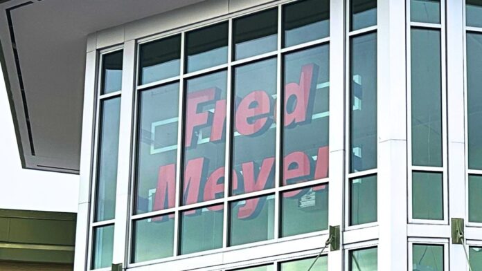 Fachada de una tienda Fred Meyer con la entrada principal y comercios ubicados en el mismo centro comercial.