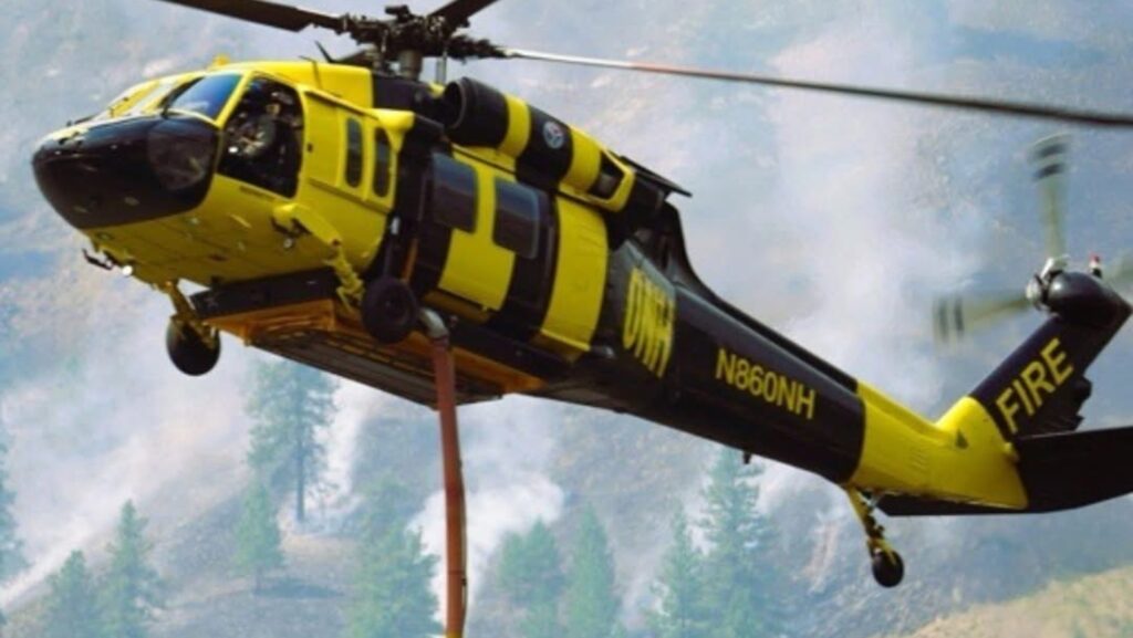 Helicóptero del Departamento de Recursos Naturales de Washington transporta agua para combatir un incendio forestal.