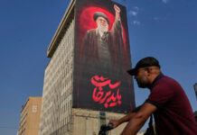 Irán ofrece recompensa de $30,000 por matar o capturar a soldados de EE.UU. Hombre en motocicleta pasa frente a una valla publicitaria con la imagen del ayatolá Ali Jamenei y un mensaje en farsi en Teherán, Irán.