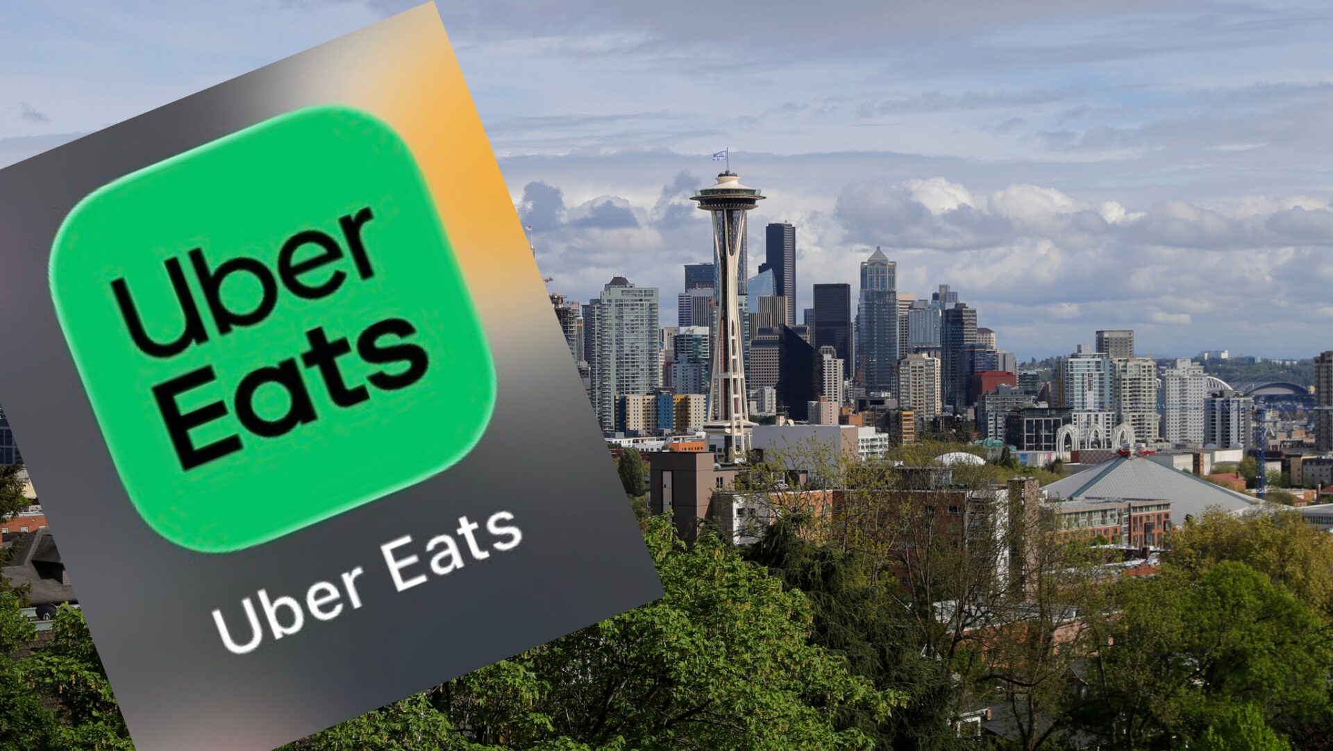 Logotipo de Uber Eats sobre una imagen panorámica de Seattle con la Space Needle y edificios del centro de la ciudad.
