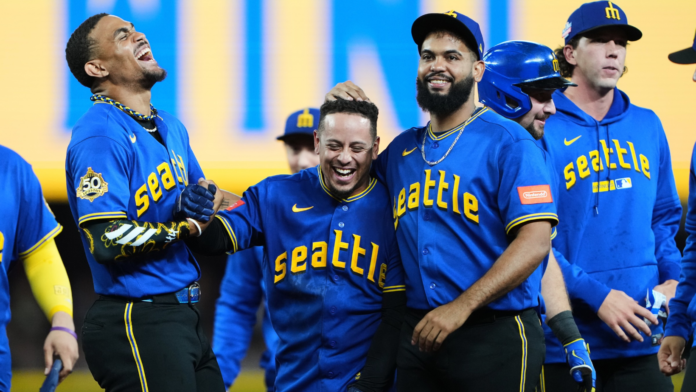 El venezolano Leo Rivas, de los Marineros de Seattle, celebra con sus compañeros Julio Rodríguez y Seranthony Domínguez tras conectar el sencillo impulsor que dio la victoria ante los Cachorros de Chicago en la décima entrada.