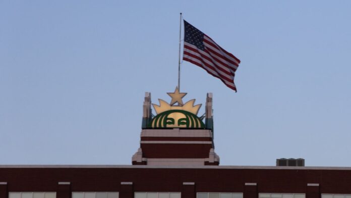 Letrero de Starbucks y bandera de Estados Unidos en la parte superior de la sede de la compañía en Seattle.