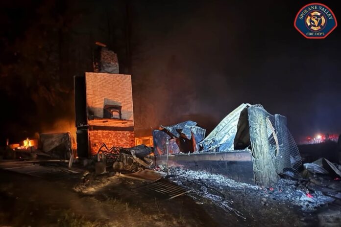 Incendios en Spokane Los restos calcinados de una vivienda reducida a escombros tras el paso de un incendio forestal en el condado de Spokane. La chimenea permanece en pie mientras aún se observan puntos calientes y humo durante la noche.