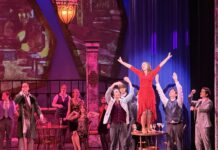 Anastasia sorprende en Everett con talento local y presencia hispana Maia Vazquez, con vestido rojo, interpreta a Lily durante una escena de Anastasia: The Musical en el Everett Performing Arts Center, rodeada por otros integrantes del elenco.