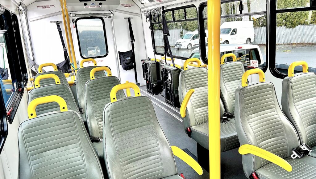 Interior de un vehículo de transporte de Homage Senior Services, con asientos, cinturones de seguridad y espacio acondicionado para pasajeros.