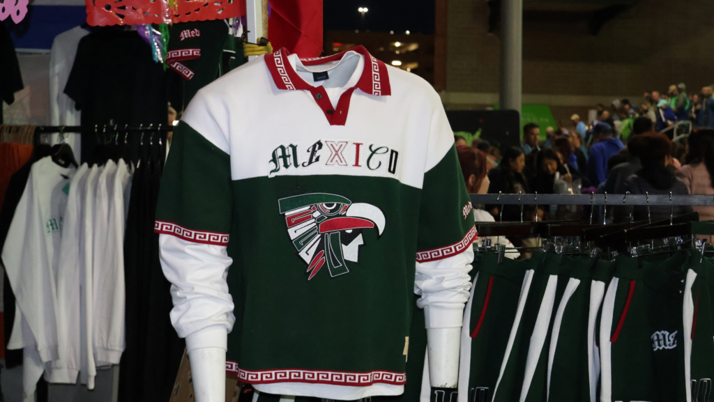 Prenda de Medium Collective en colores verde, blanco y rojo, con la palabra “México” y un diseño de águila, exhibida durante Aquí Mercado en Seattle.