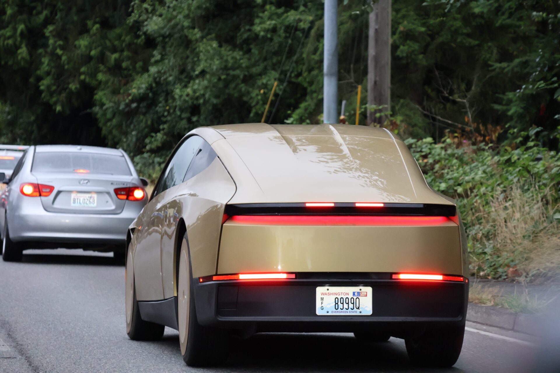 Taxi autónomo Cybercab de Tesla, de color dorado, circula por una calle cerca de Lake Ballinger, en el área de Shoreline y Mountlake Terrace, Washington.