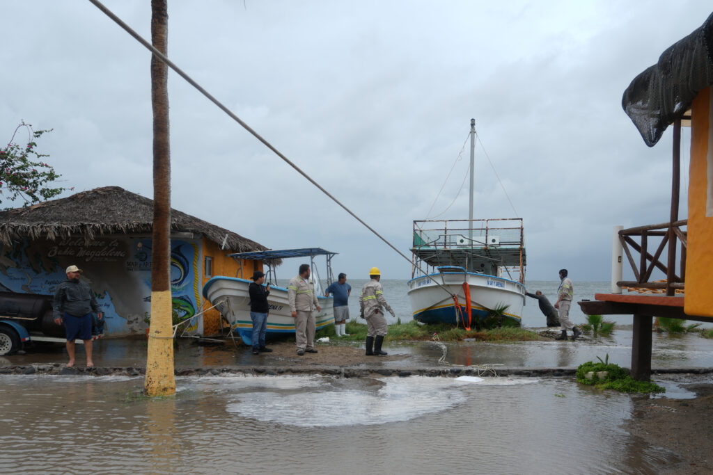 Trabajadores aseguran una embarcación en la orilla mientras se preparan para la llegada del huracán Polo en Puerto San Carlos, Baja California Sur.