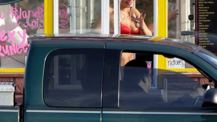 Una barista de un puesto de café tipo "Bikini Hut" sostiene dinero mientras atiende a un cliente. (Foto AP/Ted S. Warren, archivo)