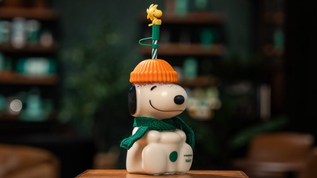 Vaso de vidrio de Snoopy de la colección Peanuts + Starbucks, con sombrero color calabaza, bufanda verde y Woodstock como adorno del popote.