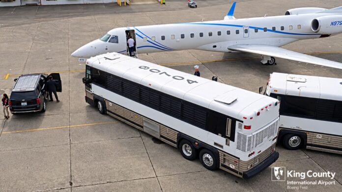 Avión y autobuses en Boeing Field durante una operación de traslado, vistos desde una posición elevada en el aeropuerto.